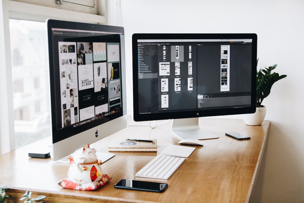 Selecting A Website Designer - two monitors on a desk showing websites